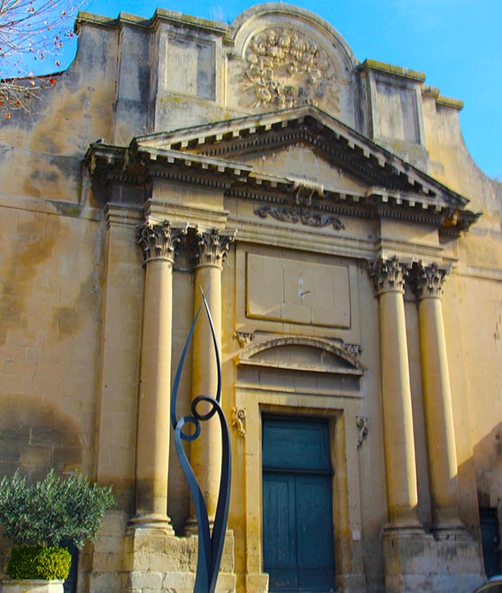 Vue sur un ancien bâtiment style romain, avec une statue devant de couleur noire.