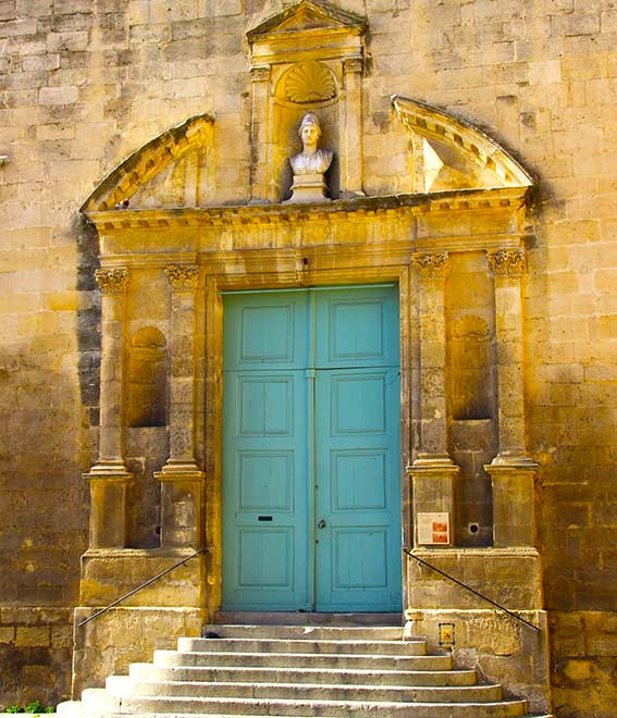 Vue sur une porte bleu d'un bâtiment ancien avec une statue au-dessus